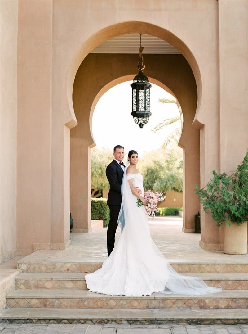 Elegant wedding portrait beneath a Moroccan arch